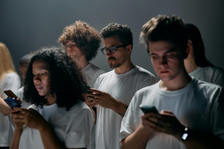 Group of young adults focused on their smartphones, embodying modern social technology and isolation.